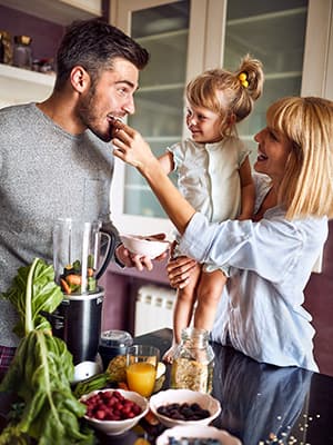 Young family preparing smoothies together in the kitchen
